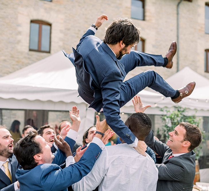 Groomsmen throwing the groom in the air