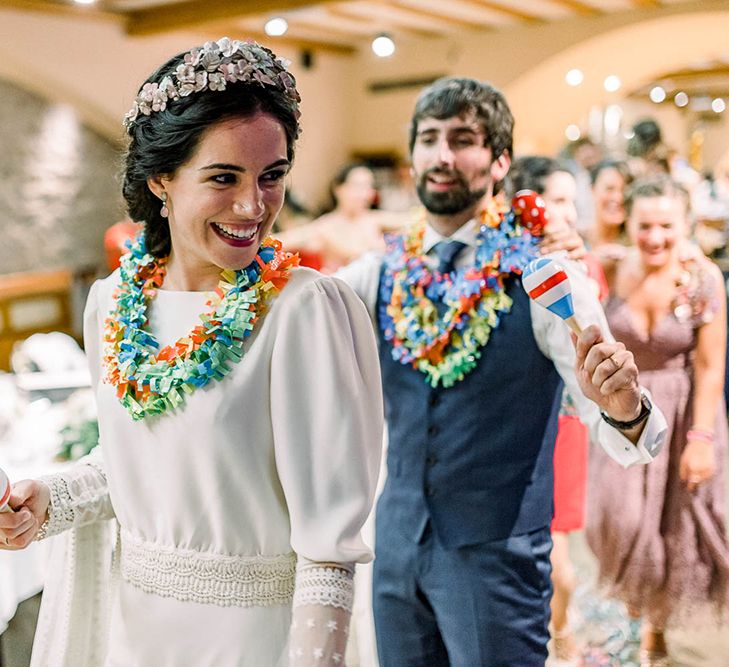 Bride and groom shaking maracas wearing colourful Hawaiian flower necklace