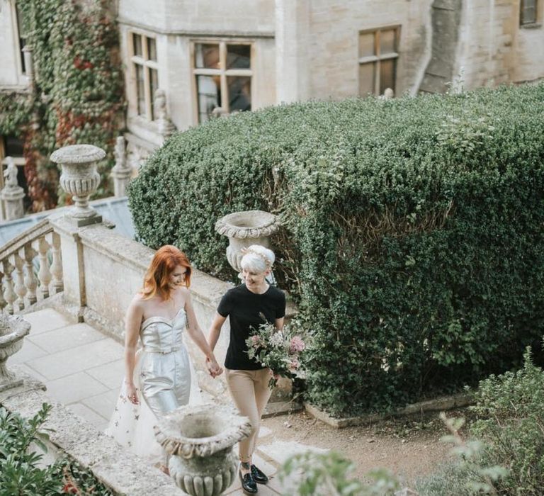 Two brides holding hands walking up the steps