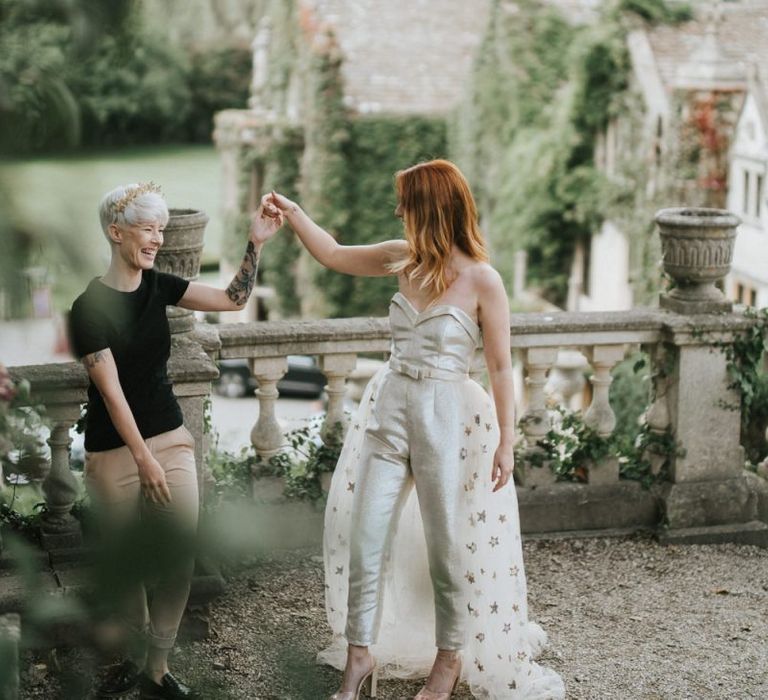 Two brides dancing on the grounds of Castle Combe Manor House in Wiltshire