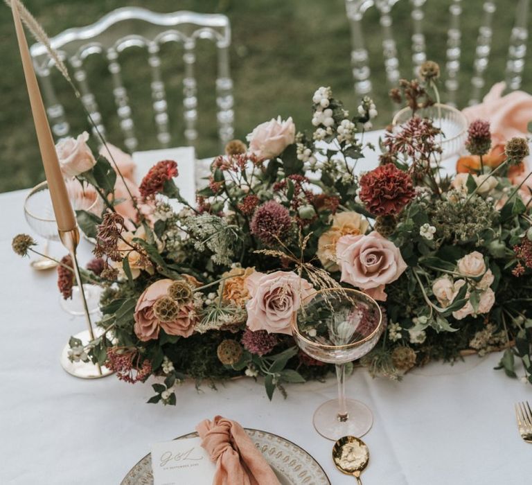 Wedding table decor with floral centrepiece, taper candles and gold cutlery