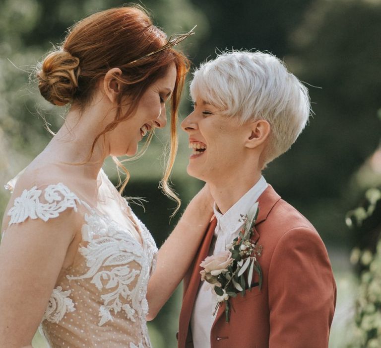 Bride in lace wedding dress and bride in rust coloured suit