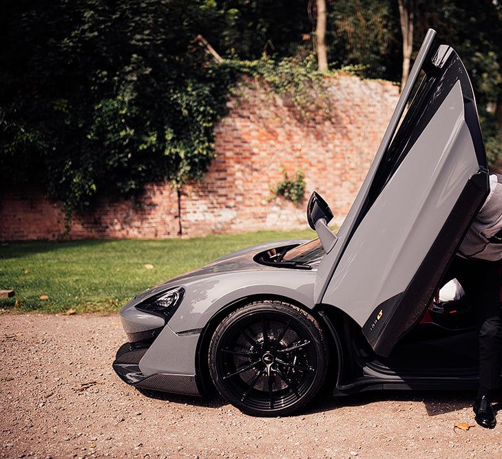 Groom stepping out of a sports car at Dorfold Hall wedding