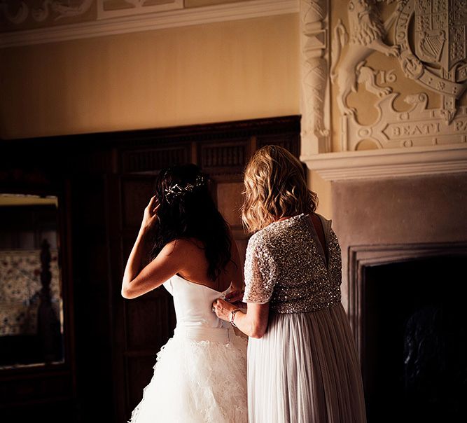 Bridesmaid helping the bride into her wedding dress