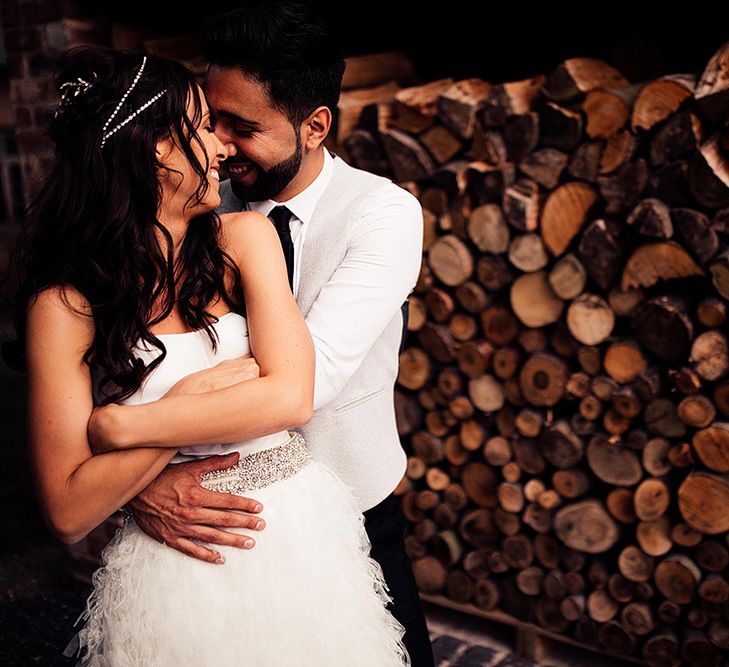 Bride and groom embracing by some logs at Dorfold Hall wedding venue