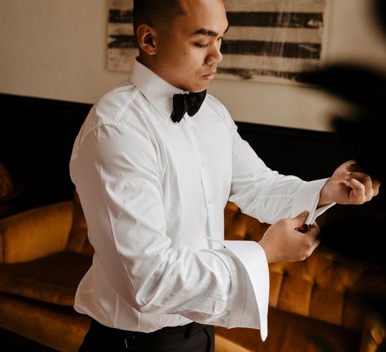 Groom puts on tuxedo for black and white colour scheme wedding