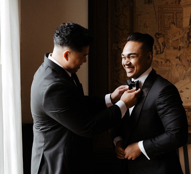 Groom puts on tuxedo for black and white colour scheme wedding