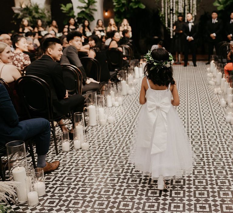 Flower girl walking down the aisle in white dress