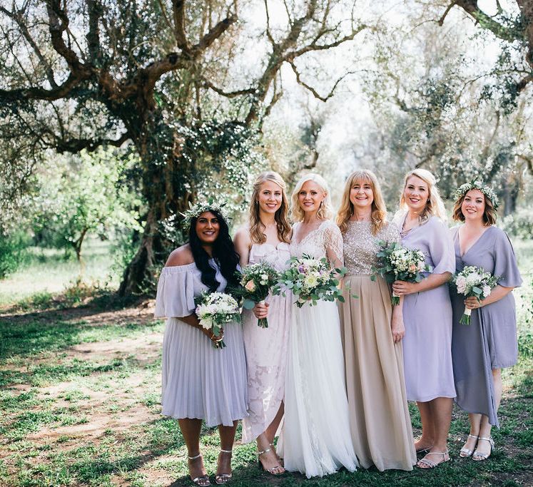 Bride in Long Sleeved Anna Kara Wedding Dress with Lace Bodice and Soft Skirt | Britten Weddings Floor Length Veil | Bridesmaids in Mismatched Lilac Dresses | Bouquets of White, Soft Pink, Purple and Yellow Flowers with Greenery | Flower Crowns | Mother of the Bride in Taupe Adrianna Papell Dress with Sparkly Bodice and Soft Skirt | Puglian Countryside Wedding with Fairy Light Altar and Olive Grove Aperitivo | Figtree Wedding Photography