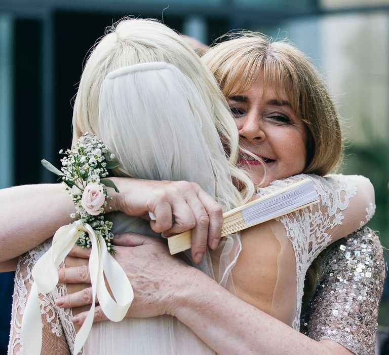 Hug from Mum | Bride in Long Sleeved Anna Kara Wedding Dress with Lace Bodice and Soft Skirt | Britten Weddings Floor Length Veil | Mother of the Bride in Taupe Adrianna Papell Dress with Sparkly Bodice and Soft Skirt | Puglian Countryside Wedding with Fairy Light Altar and Olive Grove Aperitivo | Figtree Wedding Photography