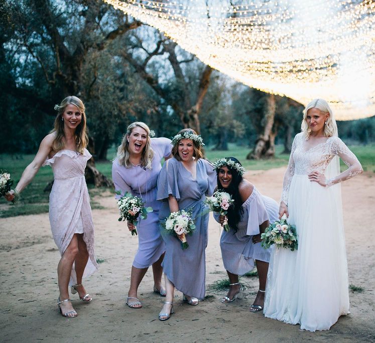 Bridal Party Girl Squad | Bride in Long Sleeved Anna Kara Wedding Dress with Lace Bodice and Soft Skirt | Britten Weddings Floor Length Veil | Bridesmaids in Mismatched Lilac Dresses | Bouquets of White, Soft Pink, Purple and Yellow Flowers with Greenery | Flower Crowns | Fairy Light Canopy | Puglian Countryside Wedding with Fairy Light Altar and Olive Grove Aperitivo | Figtree Wedding Photography