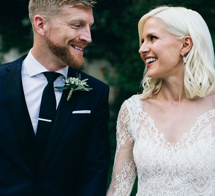 Bride in Long Sleeved Anna Kara Wedding Dress with Lace Bodice and Soft Skirt | Groom in Dark Navy Hugo Boss Suit with Waistcoat and Black Patent Shoes by Common Projects | Puglian Countryside Wedding with Fairy Light Altar and Olive Grove Aperitivo | Figtree Wedding Photography