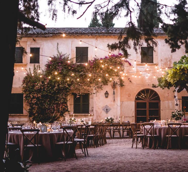 Outdoor Dining With Festoon Lights In Courtyard // Bride In Straw Hat With Leanne Marshall Wedding Dress Destination Wedding In Mallorca With Images From F2 Studios And Film By Alberto &amp; Yago