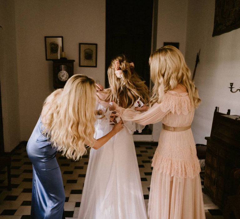 Bride being Helped into Her Wedding Dress by  Bridesmaids