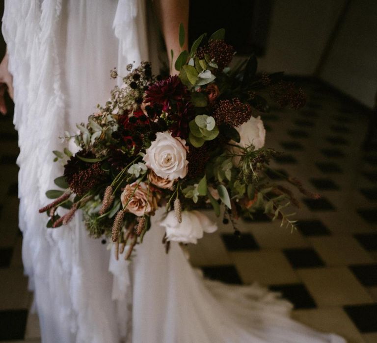 Bride Holding Her Deep Burgundy and Pink Wedding Bouquet nest to Her Romantic Wedding Dress