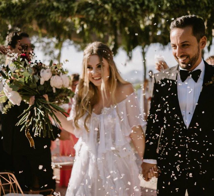 Bride and Groom Walking Up The Aisle with Confetti Being Thrown Over Them