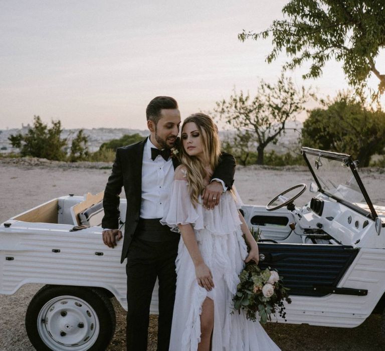 Stylish Bride and Groom Embracing at The Side of Their Jeep Wedding Car