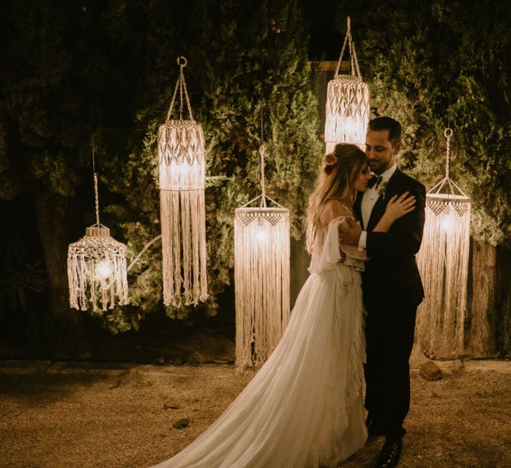 Bride in Otilia Brailoiu - Penelope Wedding Dress and Groom in Tuxedo in Front of Hanging Macrame Chandelier Backdrop