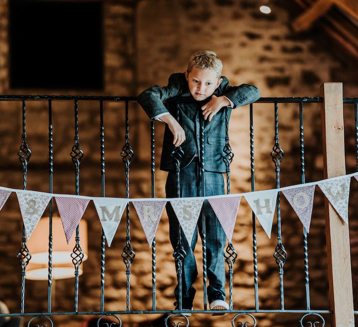 Young wedding guest leaning over the railings at Priston Mill