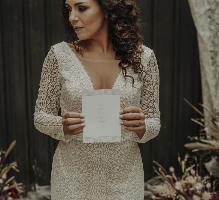 Bride in Boho Lace Wedding Dress Holding Menu Card