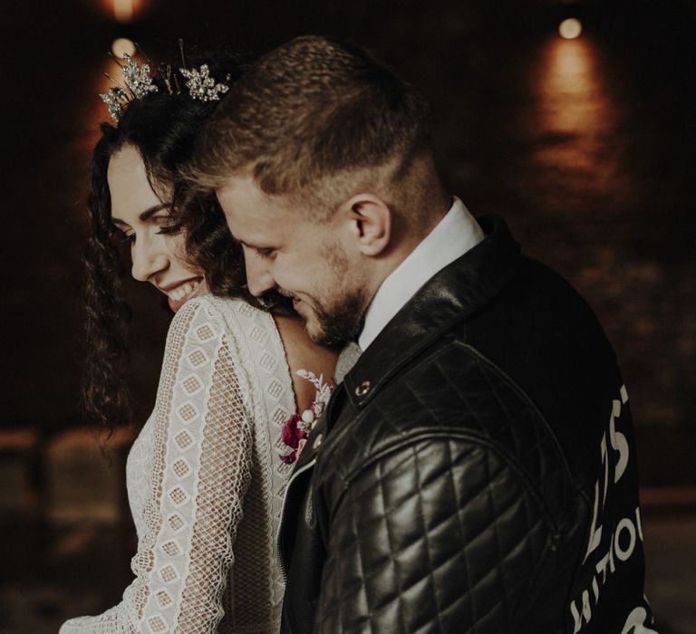 Groom in Personalised Leather Jacket Embracing Bride in Lace Wedding Dress