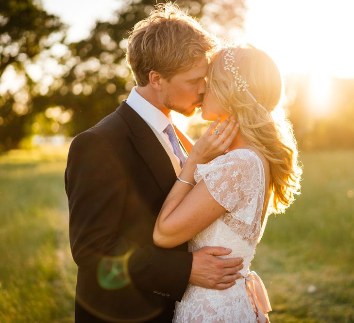 Bride in Essense of Australia Wedding Dress and Groom in Tails Kissing During sunset