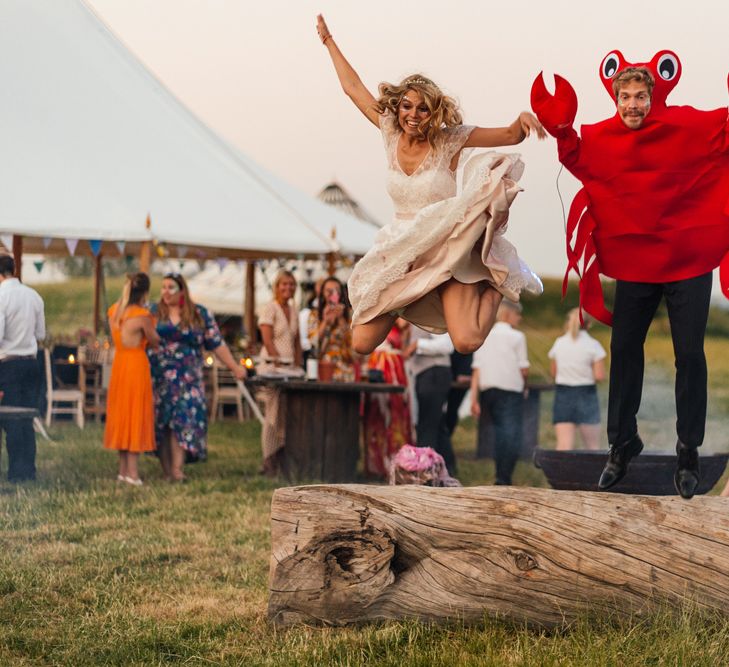 Bride and Groom Jumping off a Log Having Fun