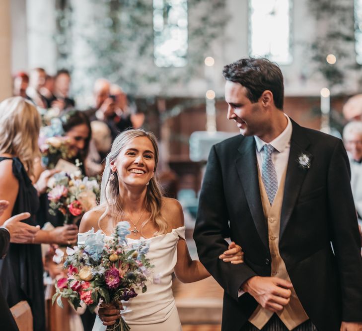 Bride and groom walk up the aisle as husband and wife after church wedding ceremony