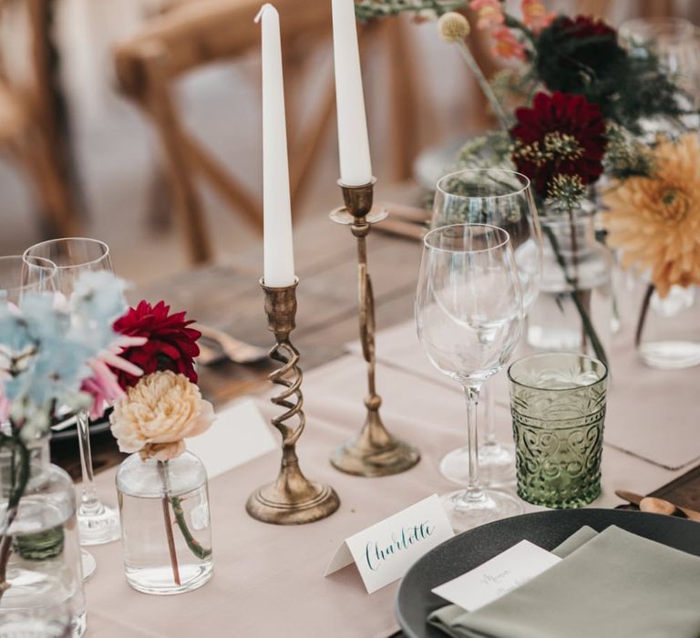 Colour plate setting with gold candlesticks, coloured tableware and bright wedding flowers