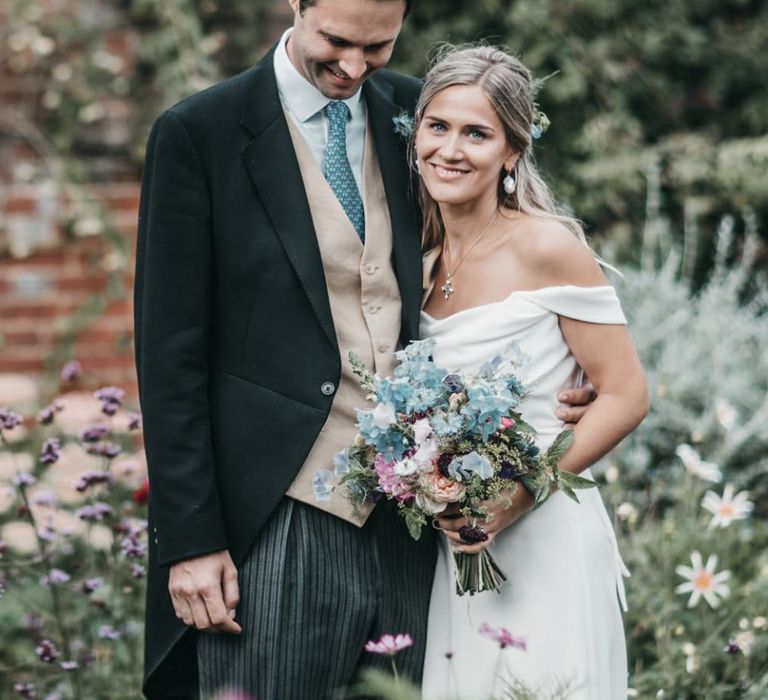 Bride and groom embracing in morning suit and Halfpenny London wedding dress for church wedding