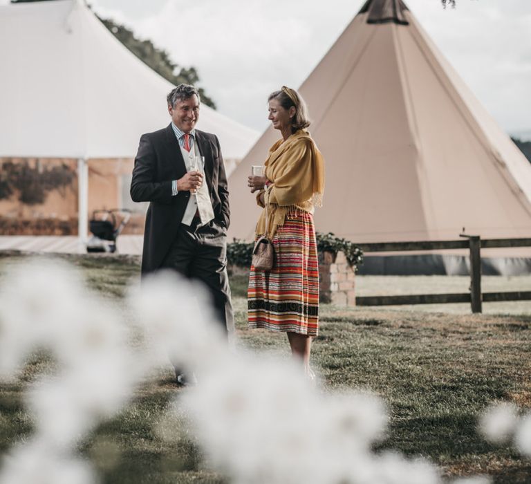 Wedding guests enjoying a drink on the lawn of outdoor wedding reception