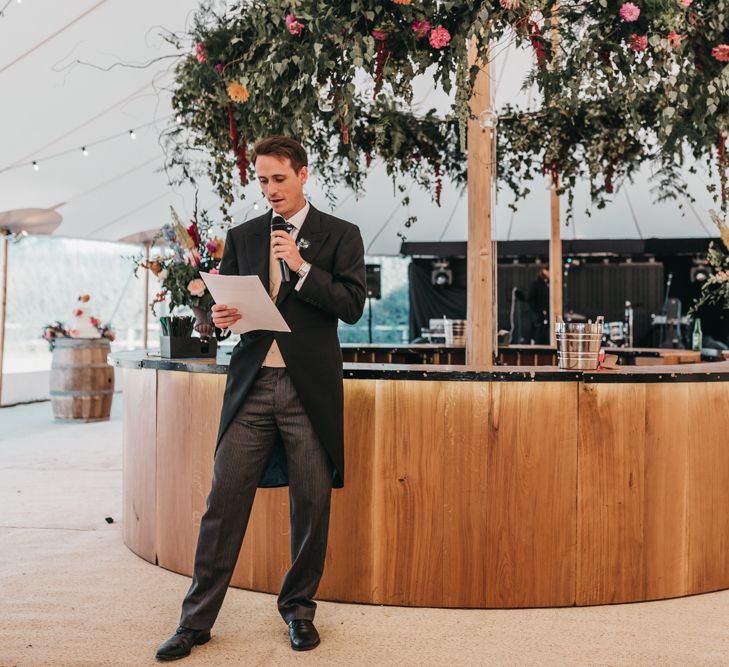 Best man delivering the wedding speech in front of the wooden bar