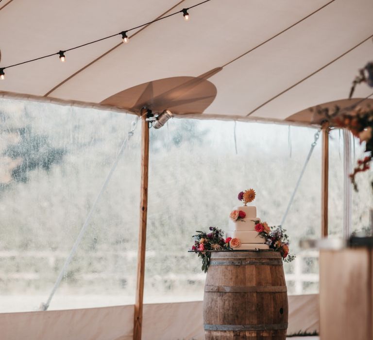 Wedding cake resting on a wooden barrel in the PapaKata Sperry tent reception