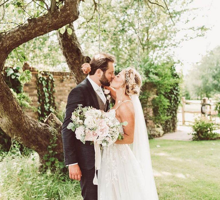 Bride and Groom Kiss holding Blush Bouquet