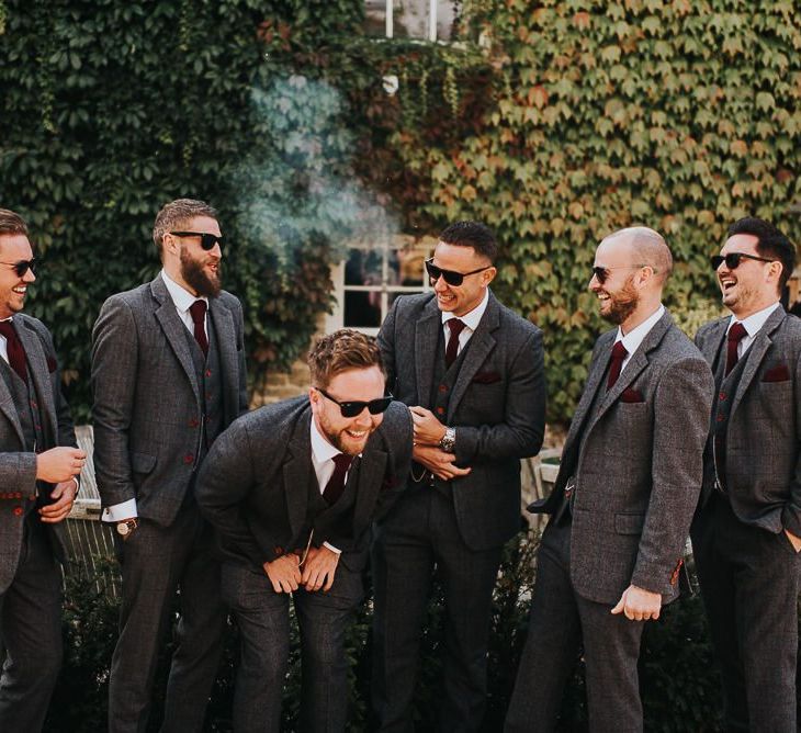 Groom and groomsmen in grey suits at wedding with light box sign and airstream photo booth