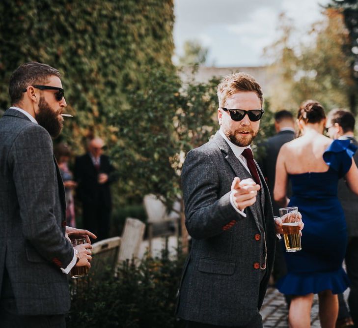 Groom in grey suit at Cotswold wedding at wedding with light box sign and airstream photo booth