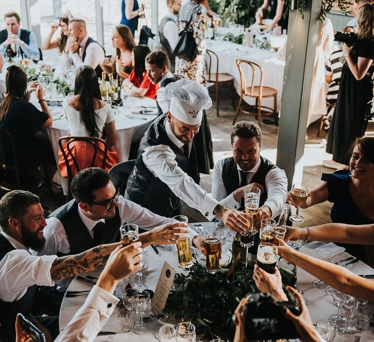 Wedding guests cheers during dinner in Stone Barn