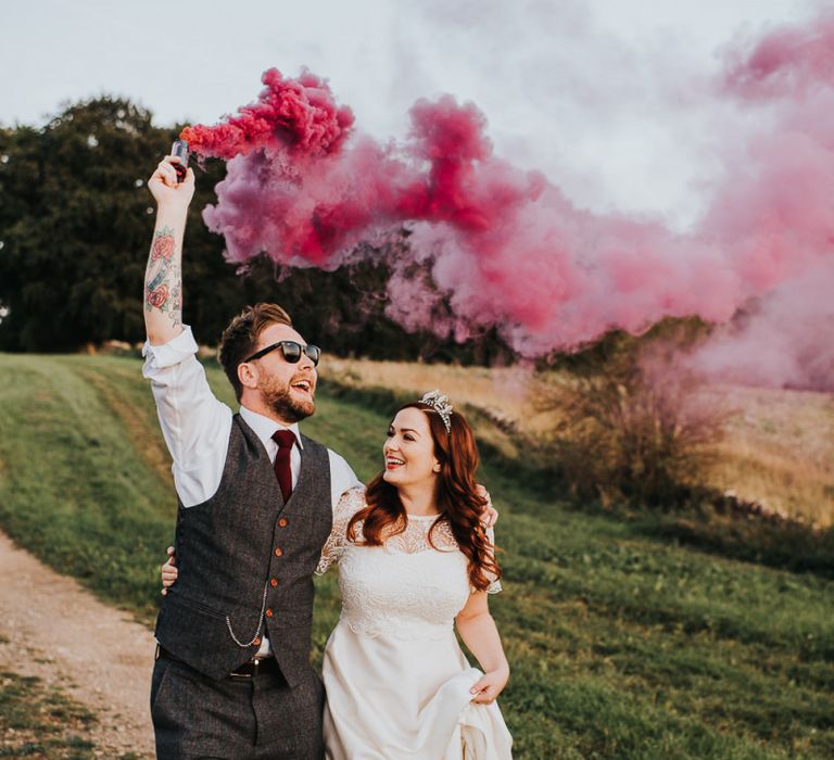 Bride and groom at wedding with smoke flares and light box sign