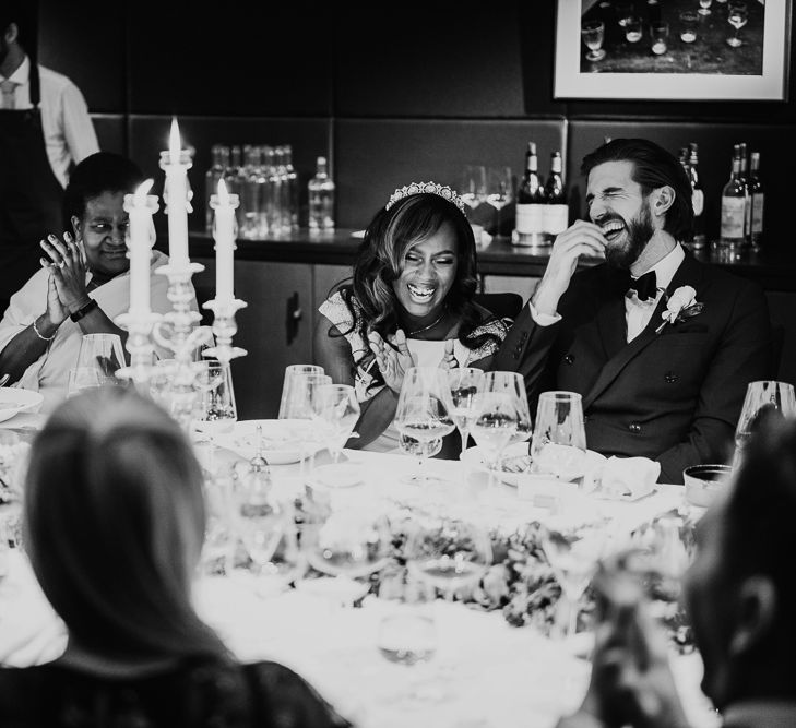 Black and white portrait of bride and groom laughing during wedding reception