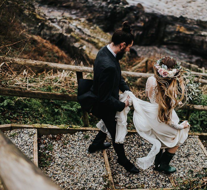 Groom Holding His Brides Wedding Dress Train Walking to the Beach