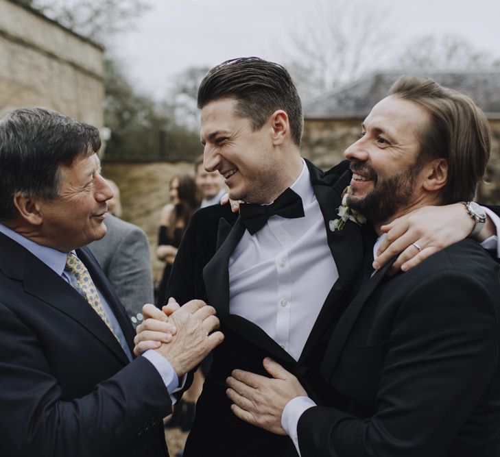 Groom in Black Tie Suit Being Congratulated by His Friends