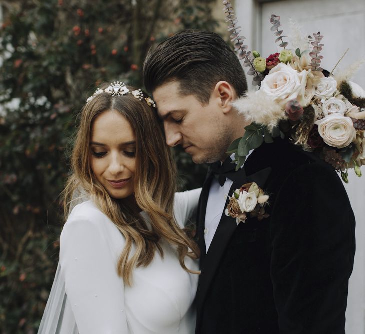 Bride in Emma Beaumont Wedding Dress and Tilly Thomas Lux Headdress and Groom in Tuxedo Embracing