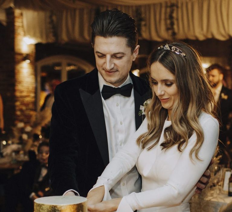 Bride in Emma Beaumont Wedding Dress and Groom in tuxedo Cutting The Wedding Cake