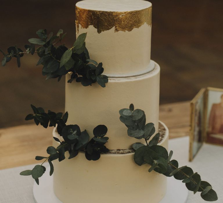 White Wedding Cake with Gold Leaf Detailing and Eucalyptus Decor