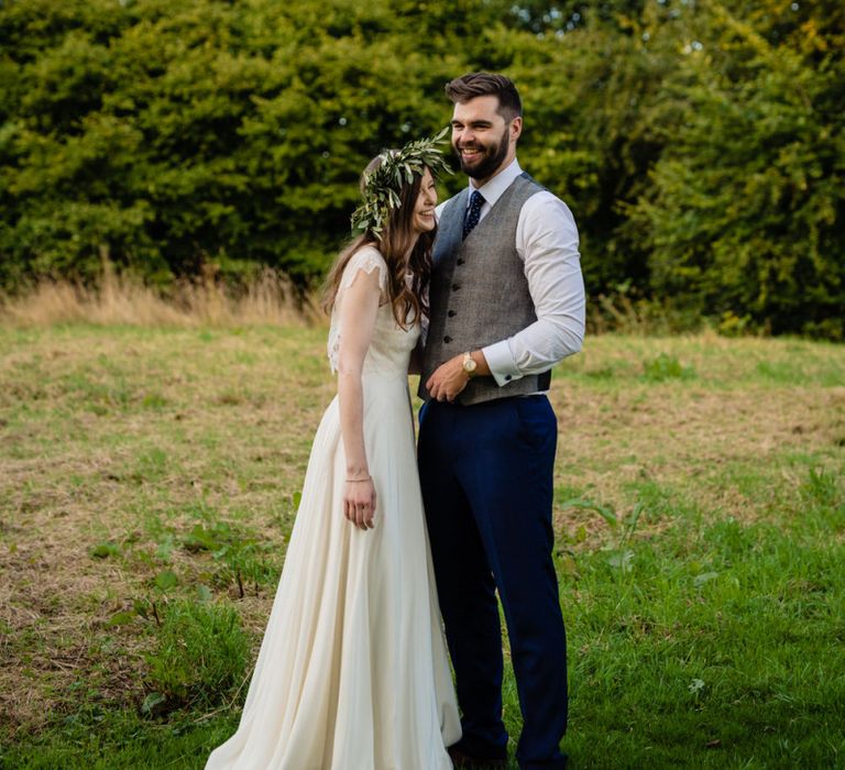 Bride in Charlie Brear Wedding Dress and Olive Flower Crown with Groom in Ted Baker Navy Suit Laughing