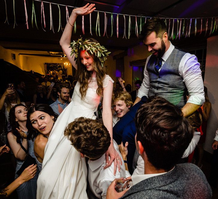 Bride in Charlie Brear Wedding Dress and Olive Flower Crown with Groom in Ted Baker Navy Suit Being Held up on the Dance  Floor