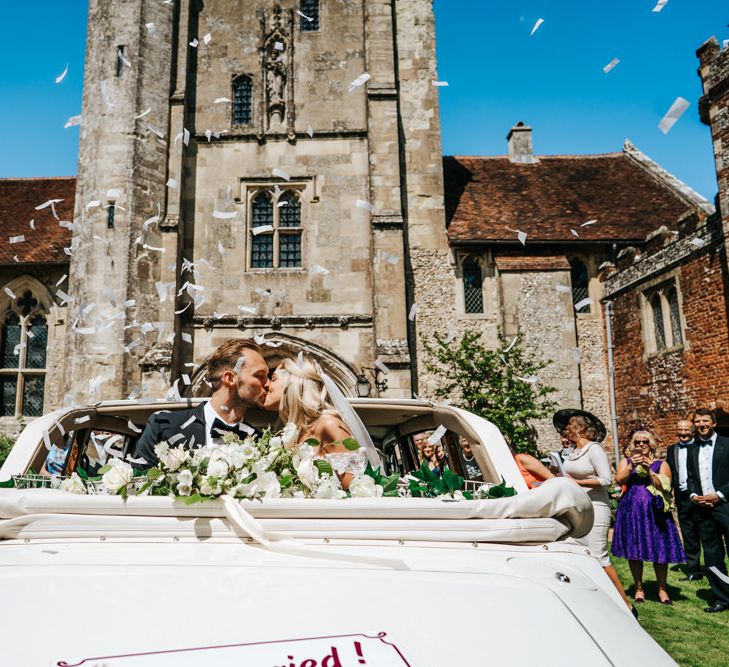 Bride and Groom on Convertible Wedding Car Covered in Confetti