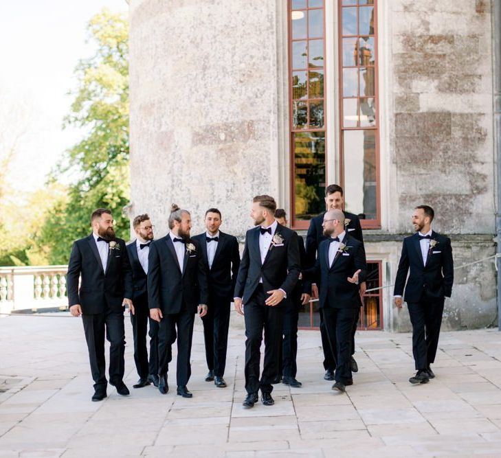 Groom with groomsmen in matching black tuxedo wedding suits