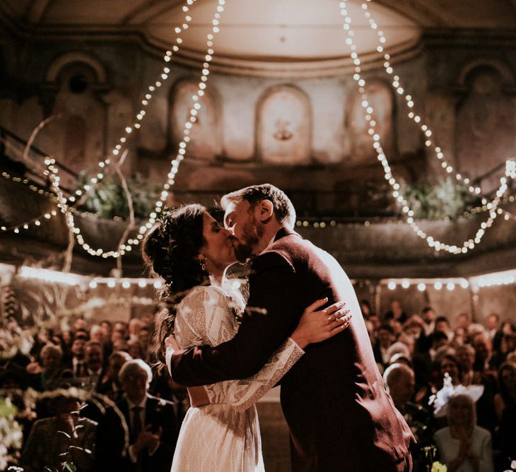 Bride in Grace Loves Lace Wedding Dress and Groom in  Brown Wedding Suit Kissing their Wilton's Hall Wedding Ceremony