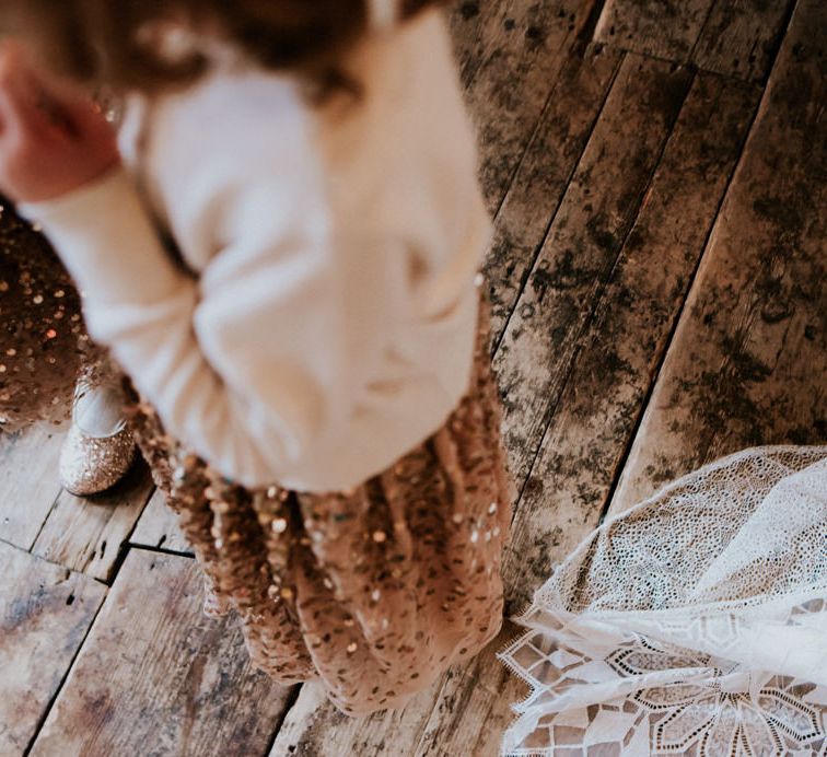 Train of Bride's Grace Loves Lace Wedding Dress and Hem of Flower Girls Gold Sequin Dress